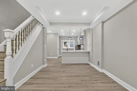 a view of a hallway with wooden floor and kitchen