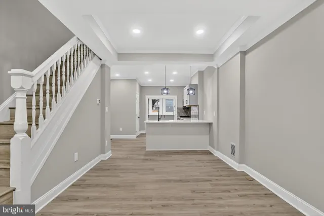 a view of a hallway with wooden floor and kitchen