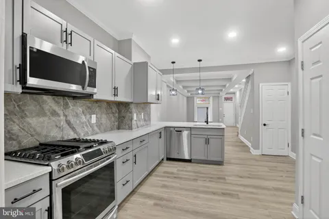 a large kitchen with stainless steel appliances granite countertop a stove and a microwave