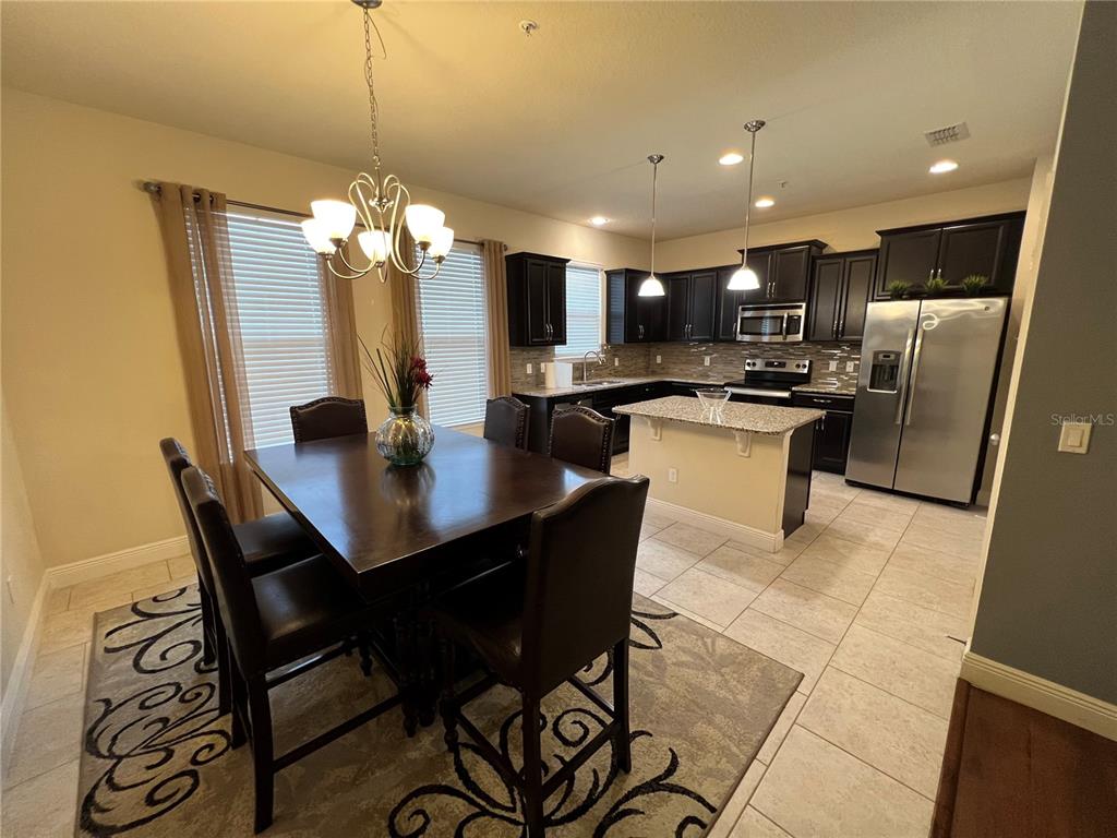 10742 Sunset Ridge Lane Orlando, FL 32832 - Photo 8 of 40 a kitchen with stainless steel appliances kitchen island granite countertop a sink a stove a dining table and chairs
