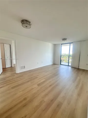 a view of a kitchen with refrigerator and wooden floor