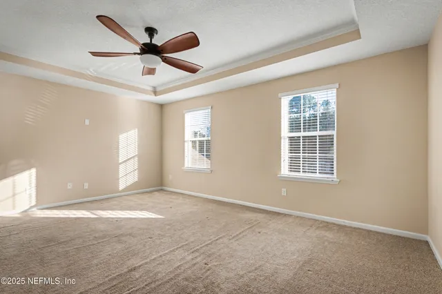 an empty room with ceiling fan and windows