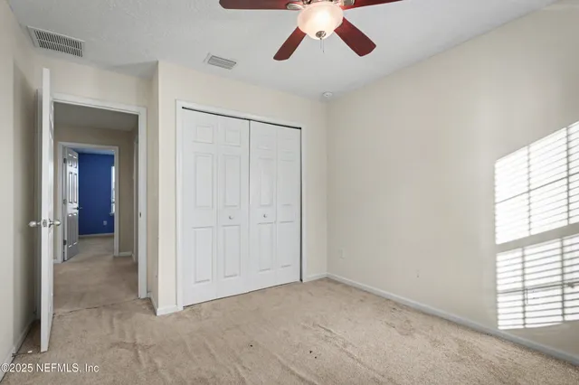 an empty room with chandelier fan and windows