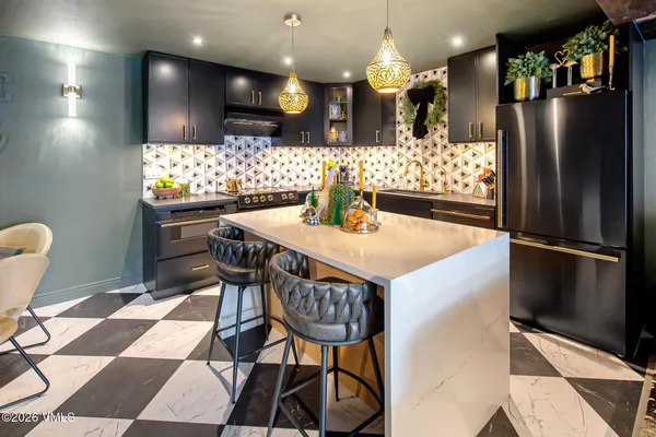 a kitchen with stainless steel appliances granite countertop a table chairs and a refrigerator