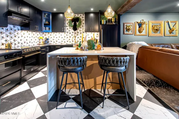 a kitchen with stainless steel appliances kitchen island granite countertop a table chairs in it and wooden floor