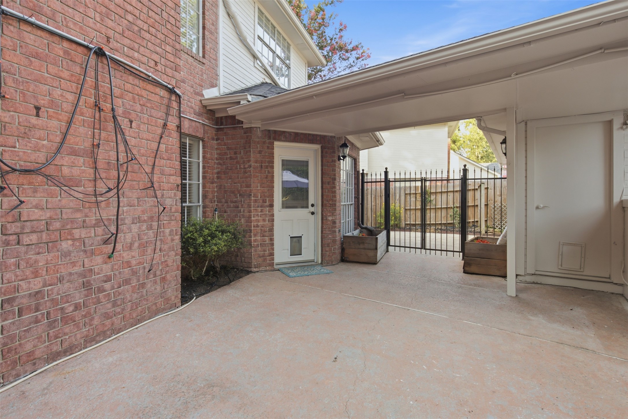 323 Magic Oaks Court Spring, TX 77388 - Photo 42 of 49 A gate and a covered walkway make getting from the garage to the house private and safe from the elements. The cords on the back of the chimney are for a built-in misting system.
