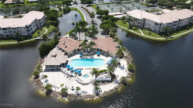 an aerial view of a house with a lake boats and trees all around