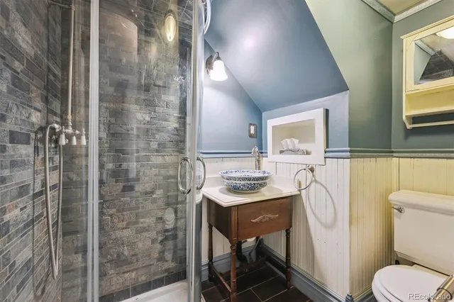 a bathroom with a granite countertop sink a toilet a mirror and shower