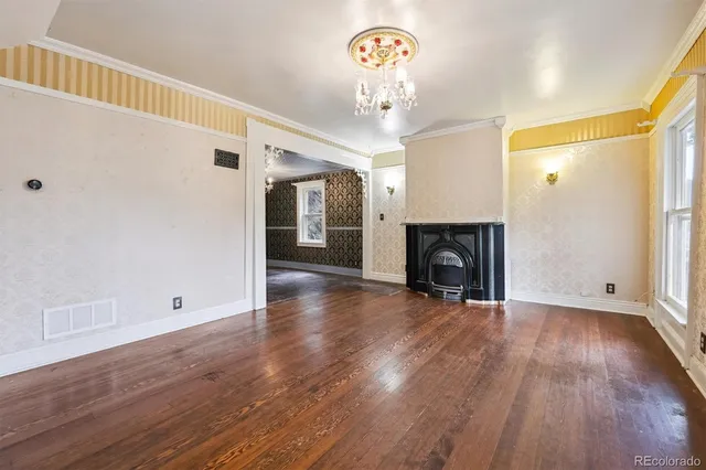 a view of an empty room with wooden floor and a fireplace