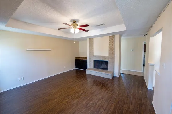 an empty room with wooden floor fireplace and fan