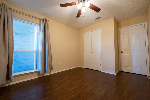 an empty room with wooden floor closet and windows
