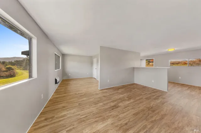 a view of a big room with wooden floor and windows