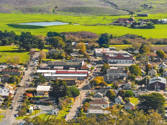 an aerial view of ocean and residential houses with outdoor space