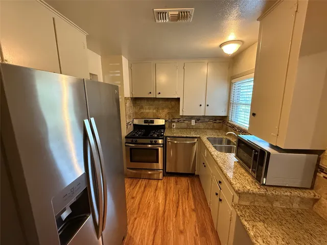 a kitchen with stainless steel appliances a refrigerator a sink a stove top oven a refrigerator and dishwasher