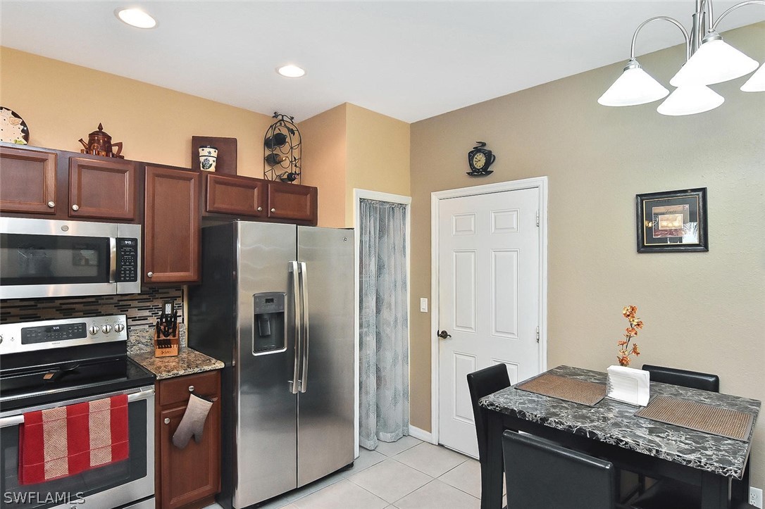 3840 Cherrybrook Loop Fort Myers, FL 33966 - Photo 7 of 32 a kitchen with stainless steel appliances granite countertop a refrigerator and a stove top oven