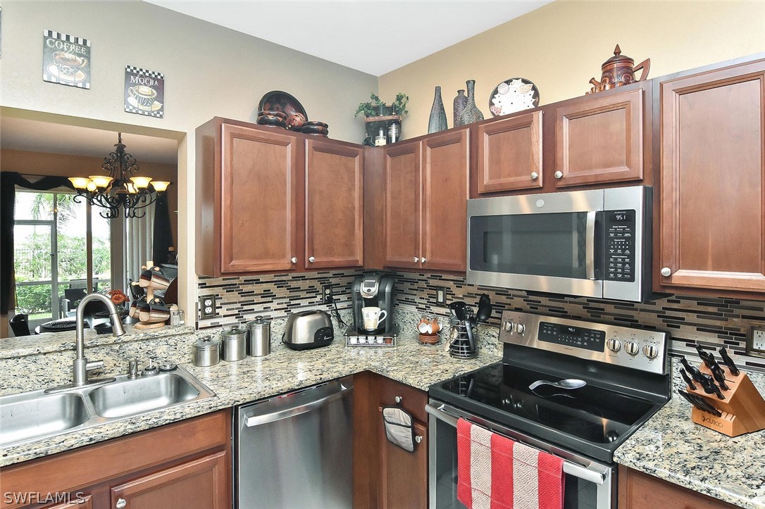 3840 Cherrybrook Loop Fort Myers, FL 33966 - Photo 9 of 32 a kitchen with stainless steel appliances granite countertop a stove a sink and a microwave