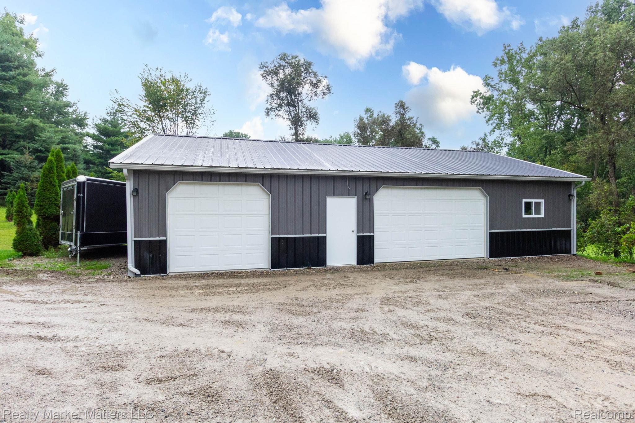 770 North Fairgrounds Road Imlay City, MI 48444 - Photo 32 of 55 Metal-sided structure featuring two garage doors, a pedestrian entry door, and a metal roof