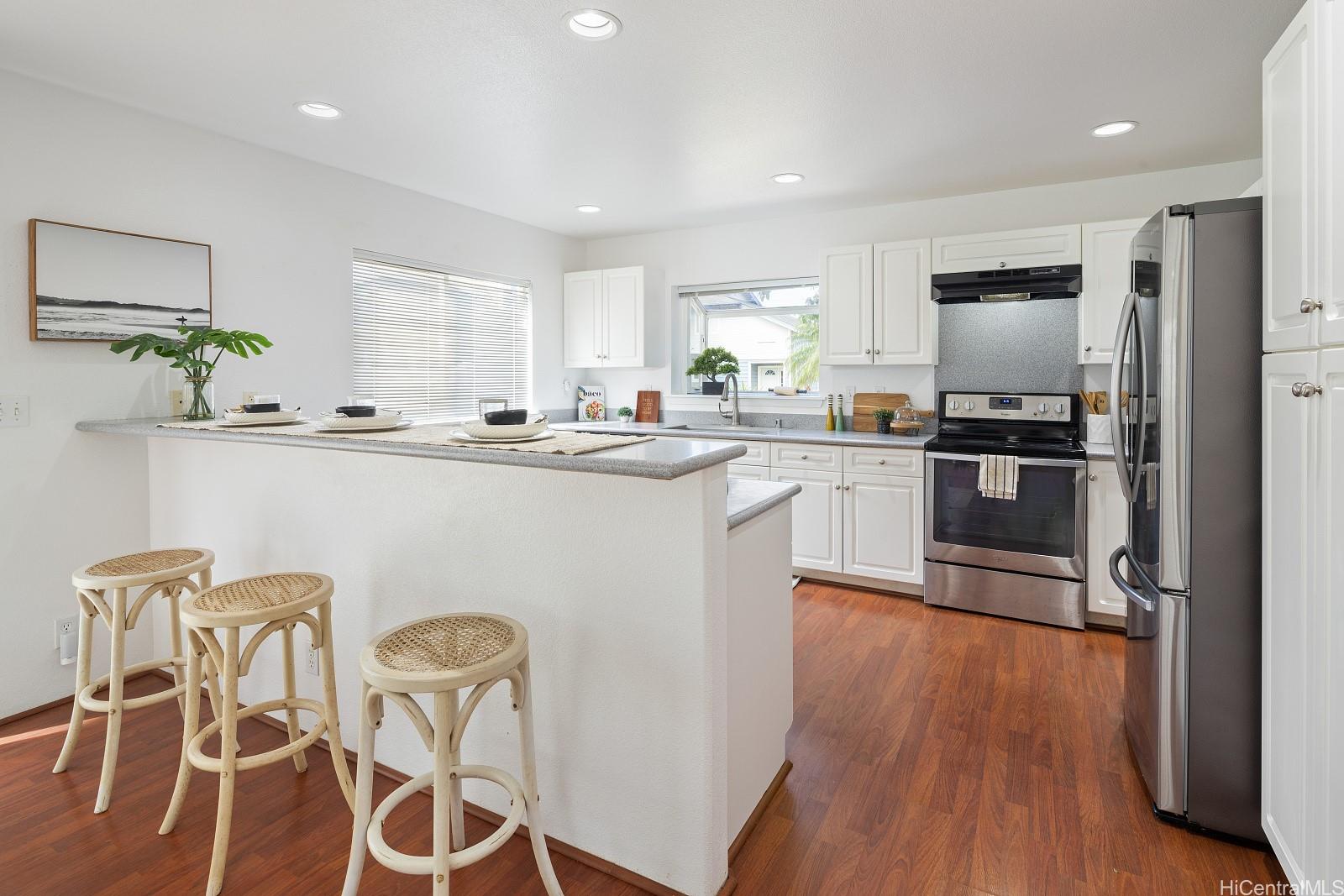92-7049 Elele Street, Unit 22 Kapolei, HI 96707 - Photo 5 of 8 a kitchen with stainless steel appliances granite countertop a stove top oven a sink a refrigerator with wooden floor and cabinets