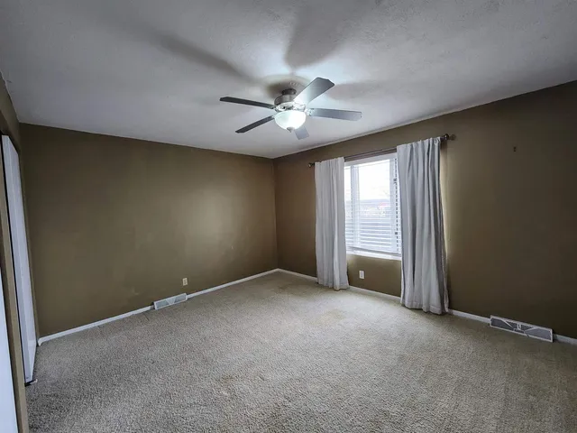 an empty room with a ceiling fan and window