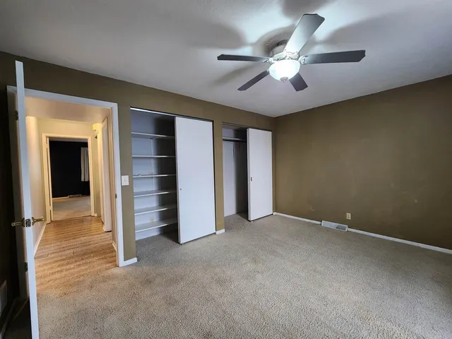 an empty room with closet and a ceiling fan