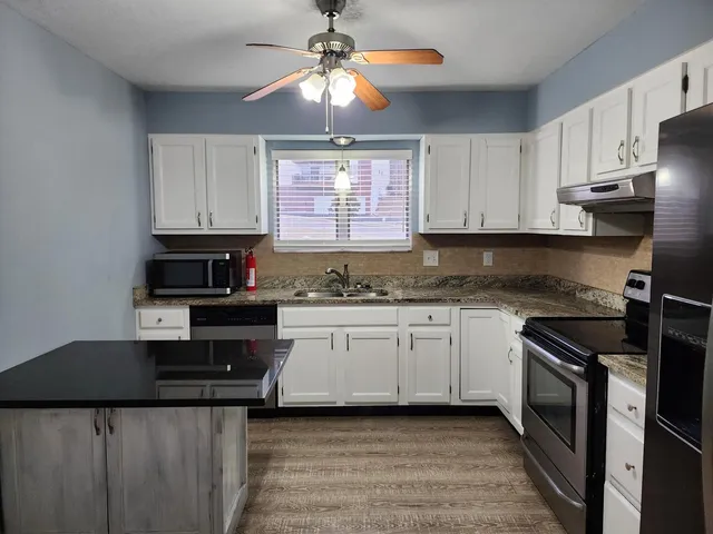 a kitchen with stainless steel appliances granite countertop a stove a sink and a microwave