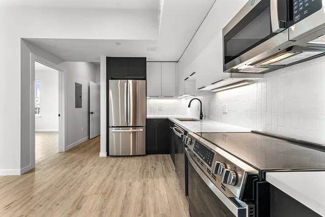 a kitchen that has a sink a refrigerator and wooden floor