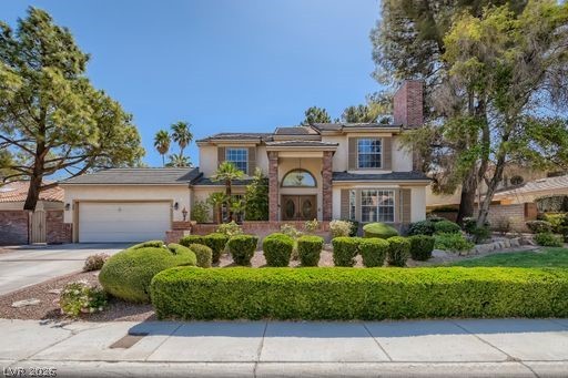 38 Hummingbird Lane Henderson, NV 89014 - Photo 1 of 1 View of front of home with stucco siding, driveway, an attached garage, a chimney, and solar panels