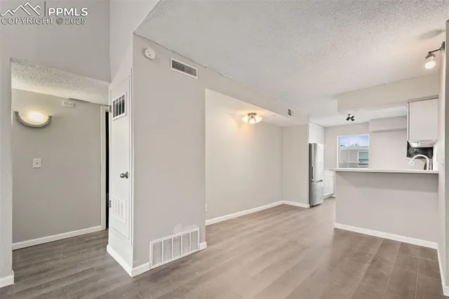 a view of a kitchen with a refrigerator and wooden floor