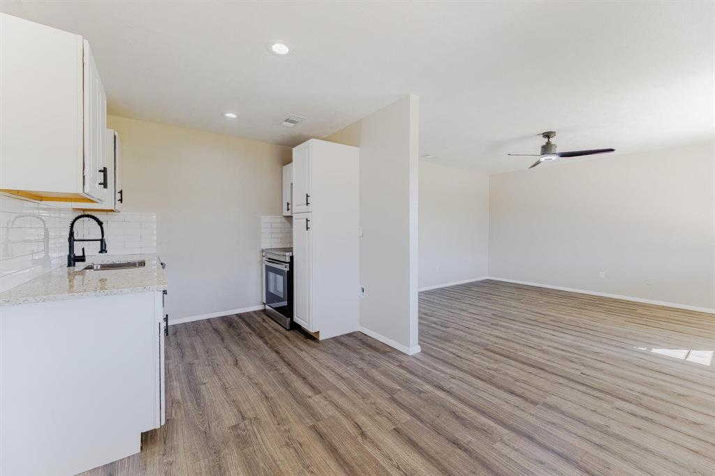 3305 Elm Grove Road Rowlett, TX 75098 - Photo 9 of 24 Kitchen with white cabinetry, tasteful backsplash, light stone counters, light wood-style floors, and stainless steel electric range