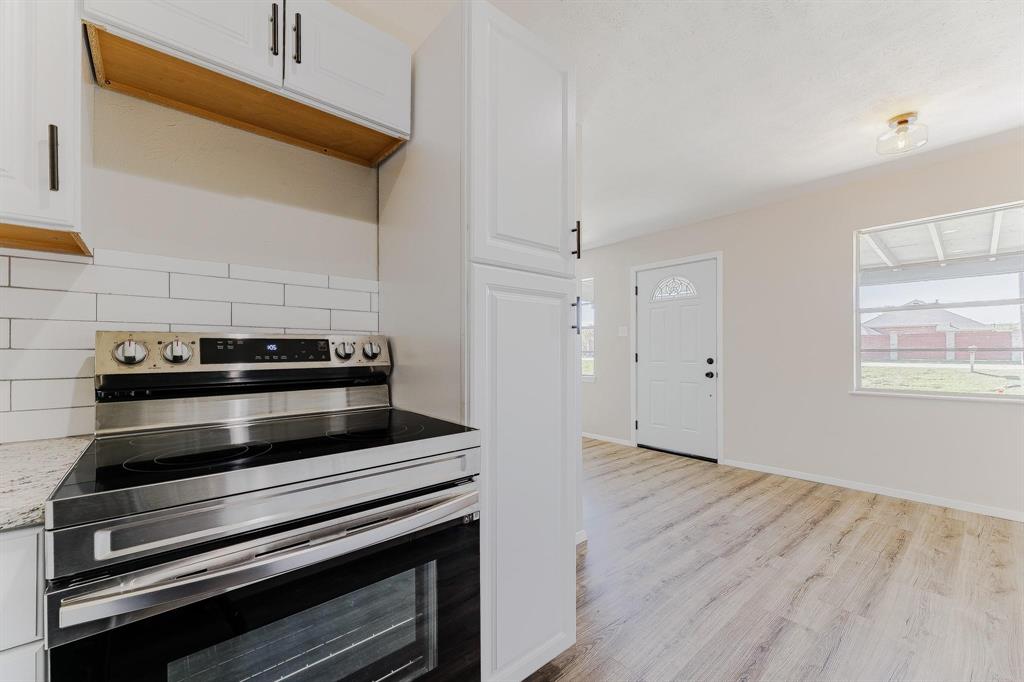 3305 Elm Grove Road Rowlett, TX 75098 - Photo 10 of 24 Kitchen with stainless steel electric range, white cabinets, light wood-style floors, and tasteful backsplash