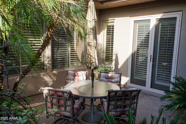 a patio with table and chairs and potted plants