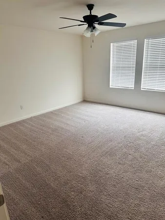 a view of a big room with windows and chandelier fan
