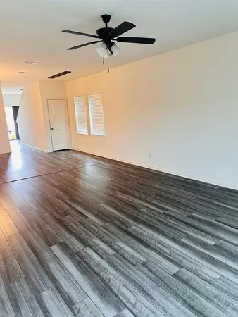a view of a room with wooden floor and a ceiling fan