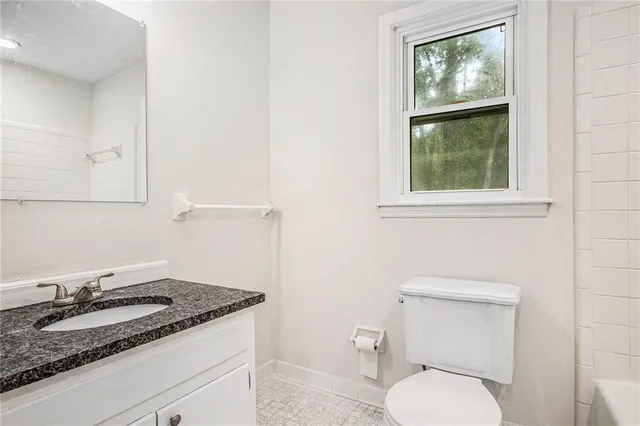 a bathroom with a granite countertop toilet sink and mirror