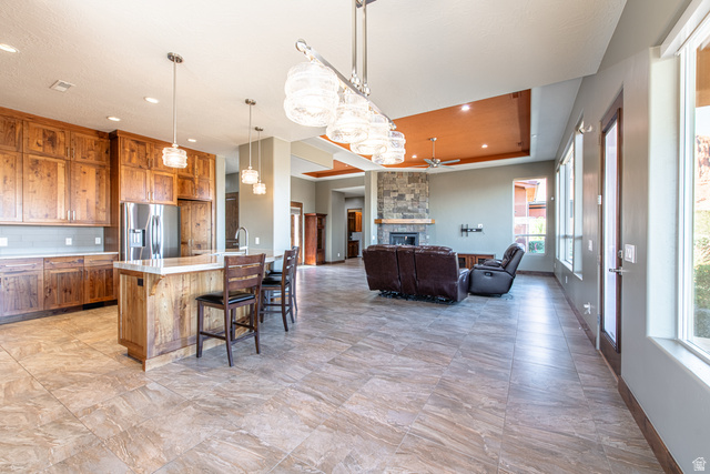 322 340 E Street Ivins, UT 84738 - Photo 19 of 61 Expansive great room featuring a kitchen with custom wood cabinetry and a large island, an open living area with a stone-clad fireplace, tile flooring, and multiple large windows