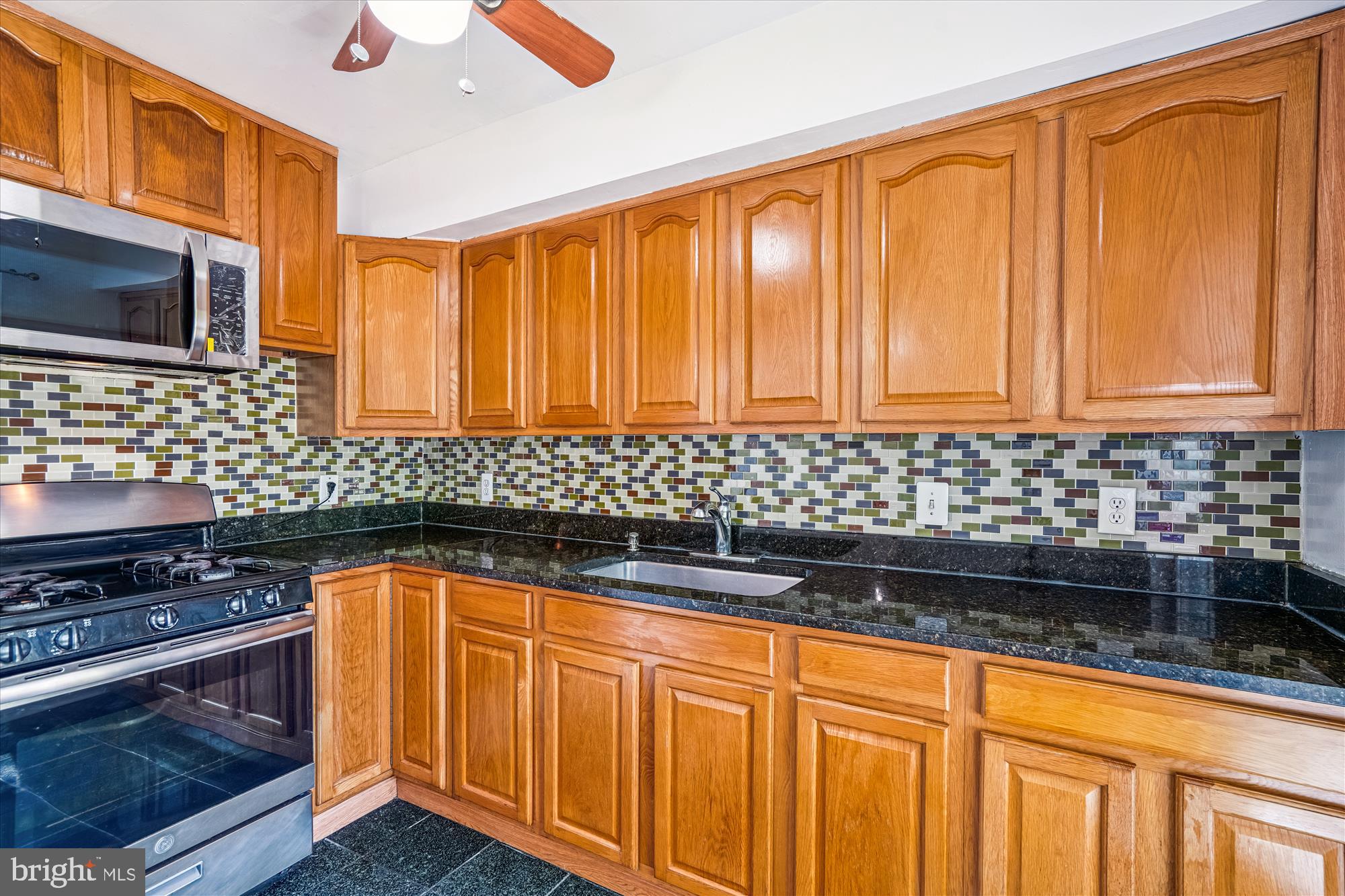 3946 Bel Pre Road, Unit 4 Silver Spring, MD 20906 - Photo 3 of 30 a kitchen with stainless steel appliances wooden cabinets and a stove top oven