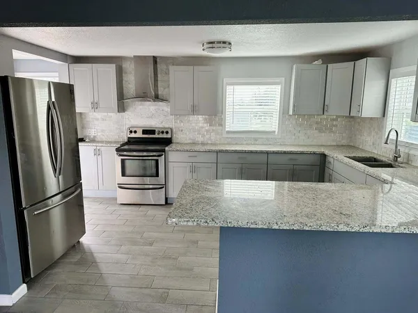 a kitchen with granite countertop a sink a stove and refrigerator