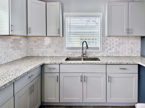 a kitchen with granite countertop white cabinets and a sink