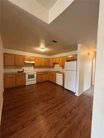 a kitchen with wooden floors and white appliances