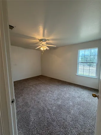 an empty room with windows and chandelier fan