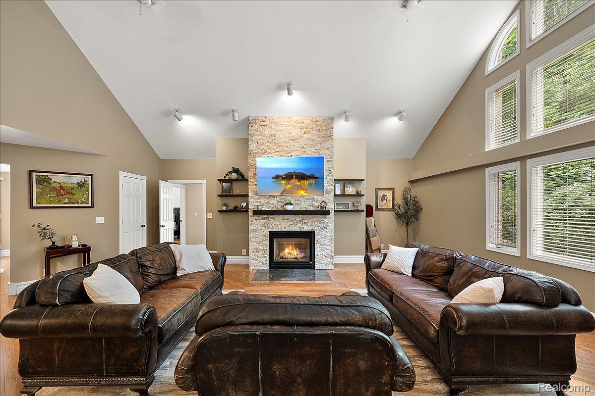 4219 Gardner Road Metamora, MI 48455 - Photo 15 of 84 Living area featuring a stone-clad fireplace, vaulted ceiling, and wood-finish flooring