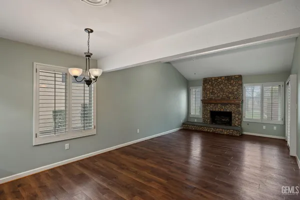 a view of an empty room with wooden floor fireplace and a window
