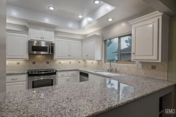 a kitchen with granite countertop white cabinets stainless steel appliances and a sink