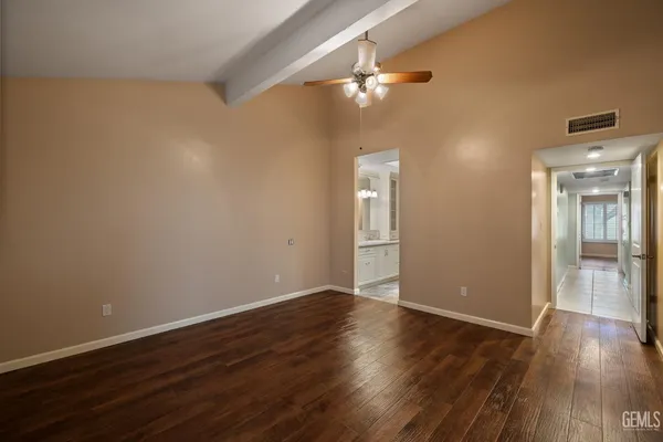 an empty room with wooden floor fan and windows