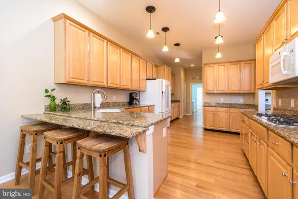 a kitchen with granite countertop wooden cabinets a sink and dishwasher with wooden floor