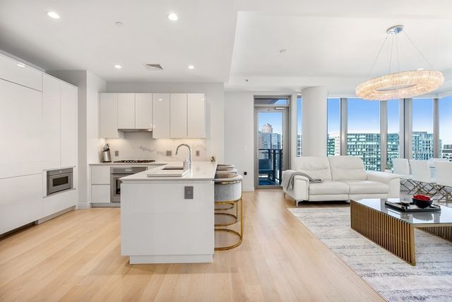 a living room with stainless steel appliances kitchen island granite countertop a couch and white cabinets
