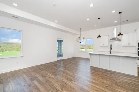 a view of a kitchen with kitchen island a sink wooden floor and a window