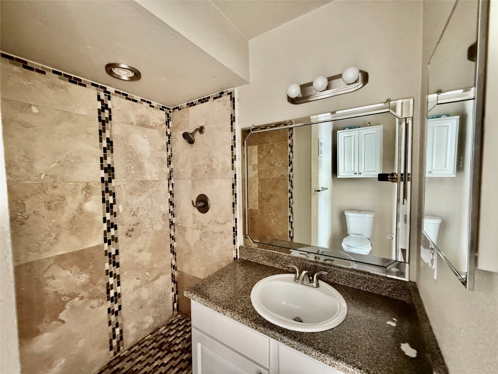 2018 West Rundberg Lane, Unit 6A Austin, TX 78758 - Photo 12 of 16 a bathroom with a granite countertop sink a mirror a vanity and shower