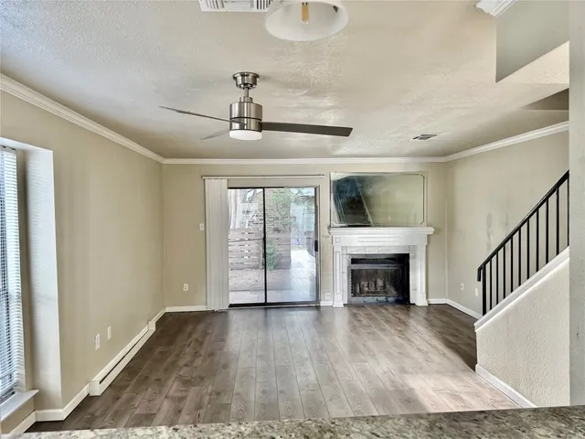 a view of an empty room with wooden floor fireplace and a window