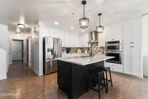 a kitchen with sink stove and white cabinets with wooden floor